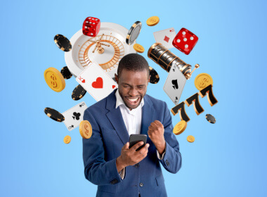 happy young African-American man playing on smartphone with casino symbols all around him