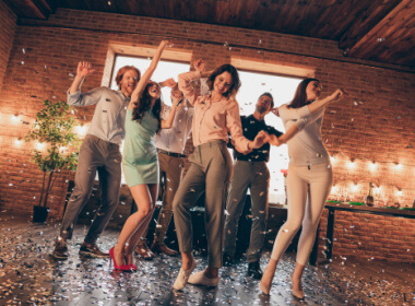 a group of friends dancing on a weekend trip in a rustic country cabin with inside brick walls