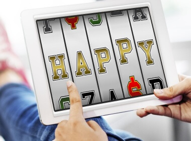 A person sitting on the sofa playing online slots with letters on the screen that spell out HAPPY