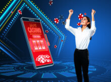 a young woman in dark pants and a white shirt smiling as she enjoys playing online slots on her mobile device