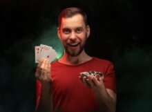 Young man smiling holding chips and a royal flush