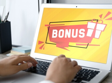 a woman at her laptop with the word bonus in large letters on the screen