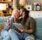 young couple happily playing at an online casino while comfortably sitting together on the sofa