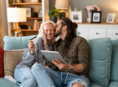 young couple happily playing at an online casino while comfortably sitting together on the sofa